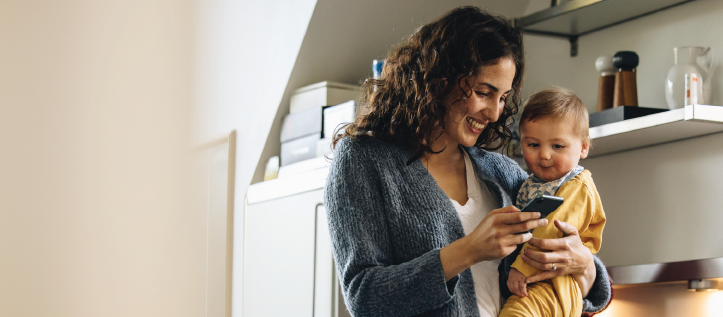 A mother reading Spirit Dental's guide on a teething timeline while holding her baby