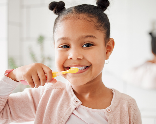 Child smiling while brushing teeth