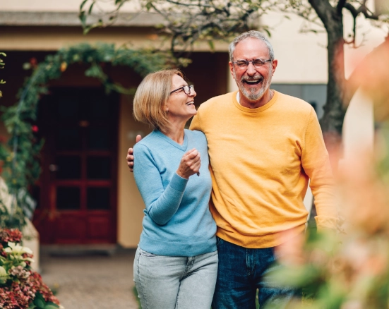 Two senior adults having a laugh while walking through the garden.
