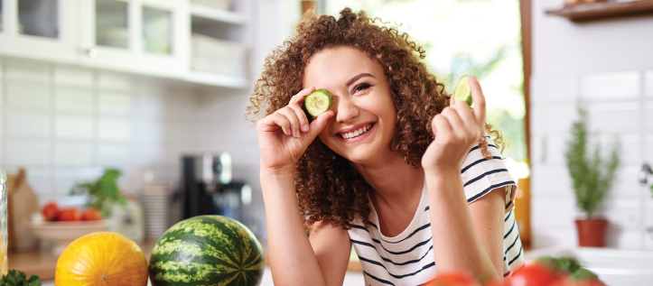 Woman in the kitchen holding a cucumber slice