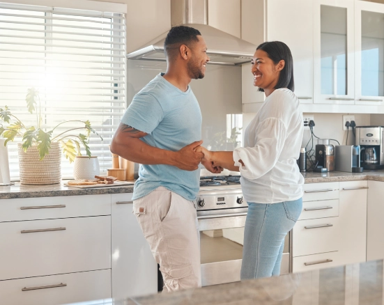 A young couple dancing and smiling in the kitchen