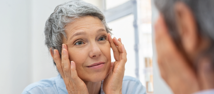 An older woman looking at her eyes in the mirror