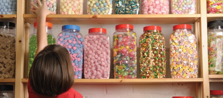 A young girl reaching for candy in a candy shop