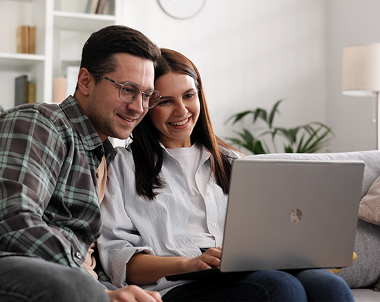Two adults sitting on a couch looking over low-cost dental plan options together.