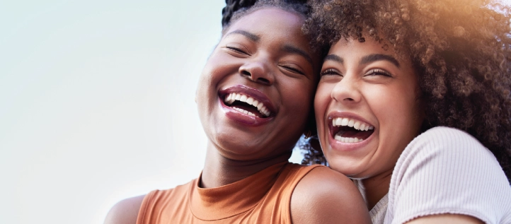 Two ladies smiling with straight teeth from braces coverage