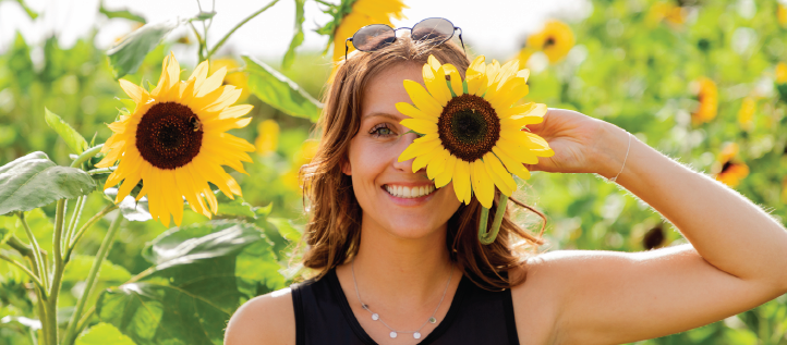 A smiling woman holding a sunflower happy about her dental plan benefits