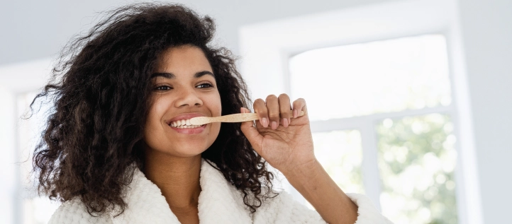 Young woman brushing her teeth in the mirror