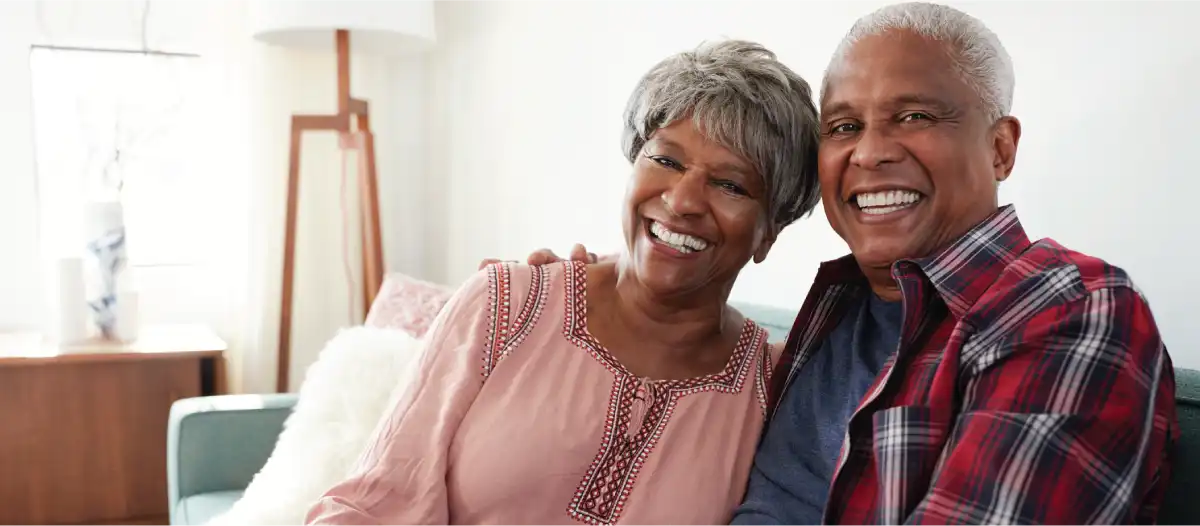 A senior couple sitting in their home smiling