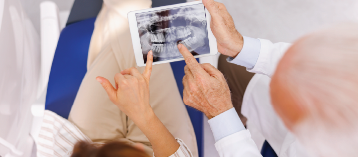 A dentist going over a x-ray of his patients teeth with her