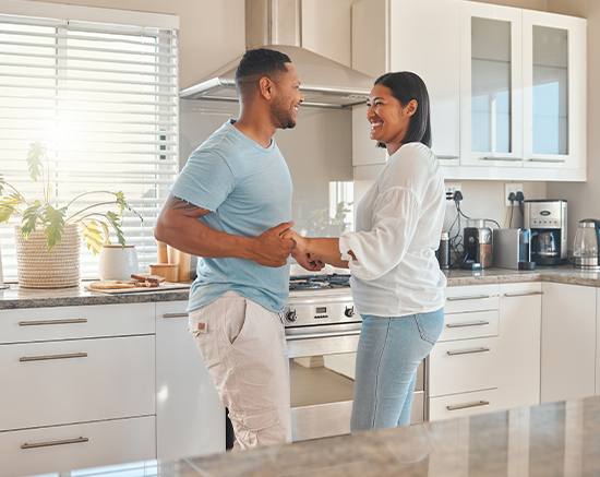 A young couple dancing and smiling in the kitchen