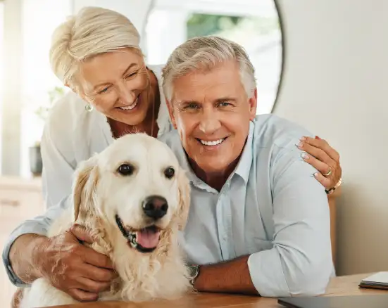 A retired couple with their dog, smiling and happy to have senior dental coverage.