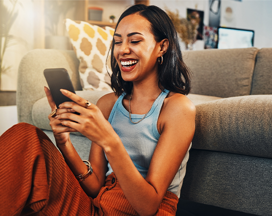 A young woman smiling at her phone while browsing Spirit Dental insurance plans