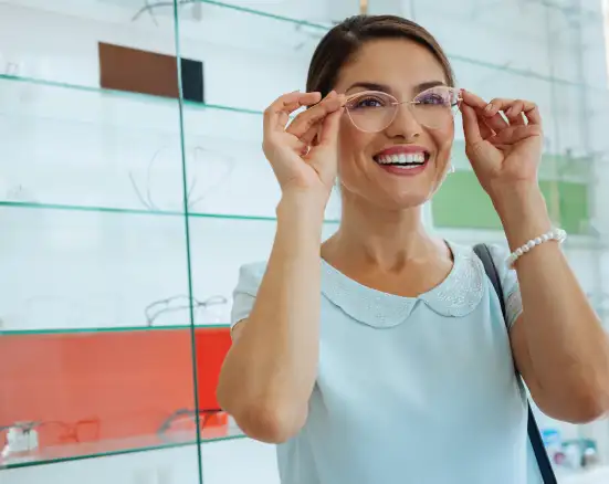 A smiling woman trying on new glasses with her new vision coverage