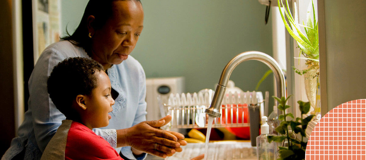 Woman washing dishes with young child