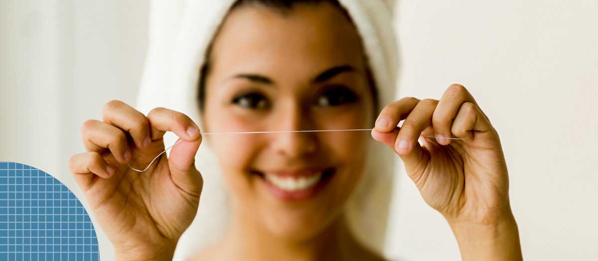 Woman holding up floss in bathroom