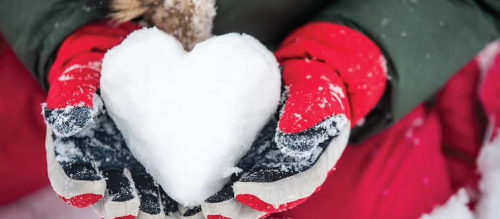 Hands holding a heart made of snow