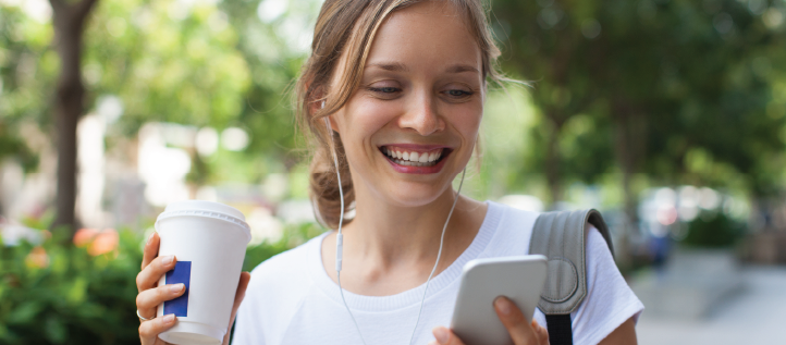 A young woman smiling while reading Spirit Dental's tips on how to keep retainers clean on her phone.