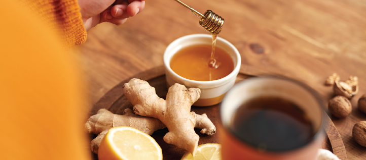 A person making tea with honey, ginger and lemons