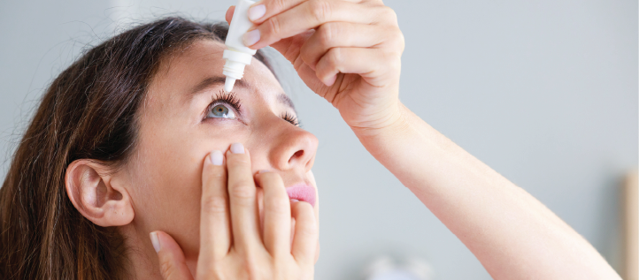 A young woman putting eye drops in her dry eyes