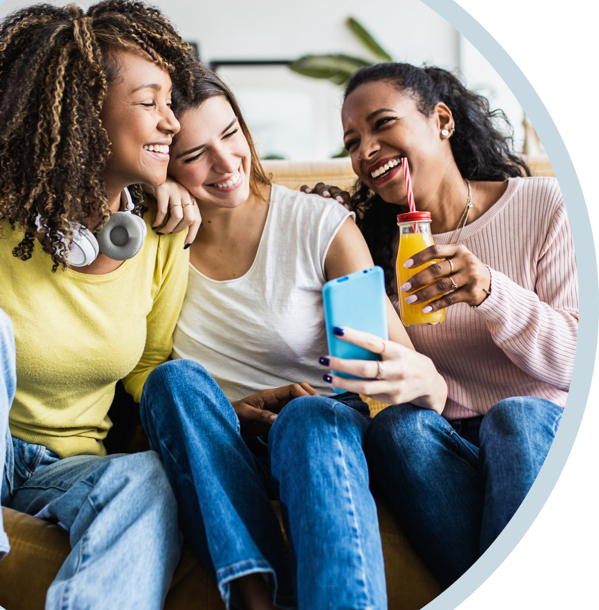 Three friends smiling, looking at a phone and enjoying beverages, with happy, confident smiles, with Spirit Dental coverage.